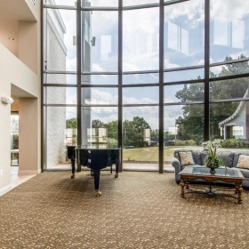 a lounge with a piano, couch and large windows